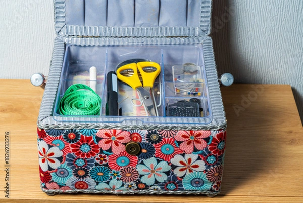 Fototapeta Open colourful sewing box with scissors, needles and a measuring tape.  Needlecraft or hobby concept