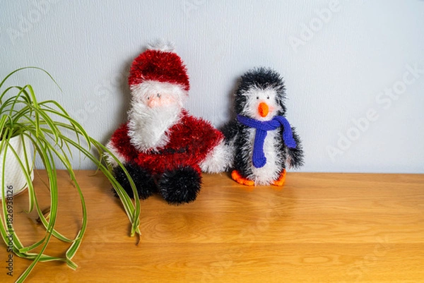 Fototapeta Toy Santa Claus with a woollen penguin and scarf on a table