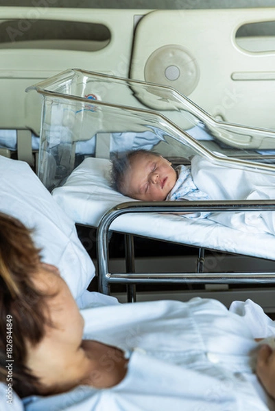 Fototapeta New mother looking at sleeping newborn baby in hospital