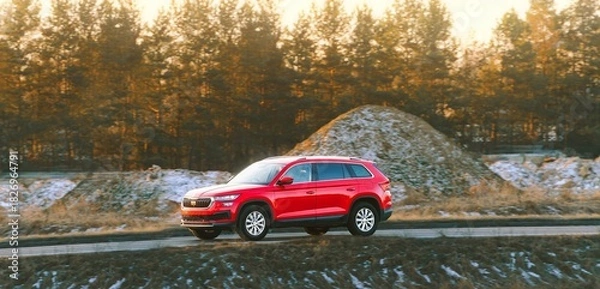 Fototapeta Compact red SUV moving on paved road
