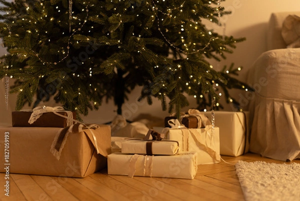 Obraz Christmas gifts under the tree with warm lighting in a cozy interior

