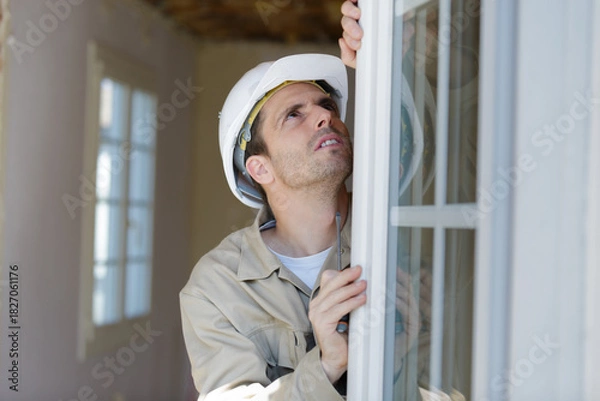 Obraz a male builder is installing window