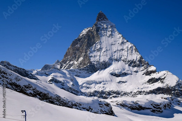 Obraz Close view of the Matterhorn covered in winter snow, rising sharply under a deep blue sky. Iconic Swiss alpine landscape with dramatic textures and prisitine mountain scenery.
