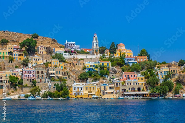 Obraz Landscape view of Symi town on Symi island with colorful neoclassical houses and a church tower, Greece