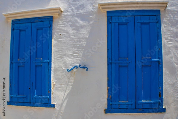 Fototapeta Windows with blue closed shutters on a white wall, Symi island, Greece
