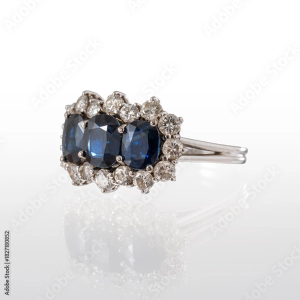 Fototapeta 18kt white gold ring with three sapphires and brilliant-cut diamonds, photographed on a white background with reflection