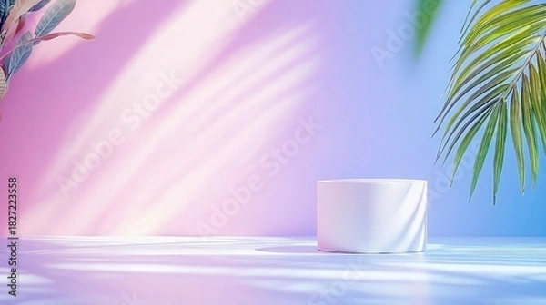 Fototapeta A clean white cylinder pedestal sits on a reflective surface, bathed in soft, diffused light with dappled shadows from tropical leaves. The background transitio