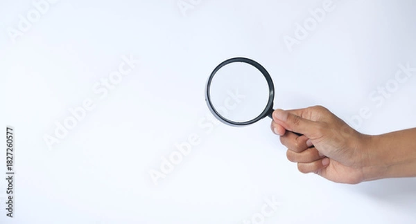 Fototapeta Close-up holding a magnifying glass on a white background.