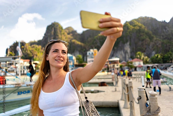 Fototapeta Woman taking a selfie in El Nido, Philippines, with stunning island scenery