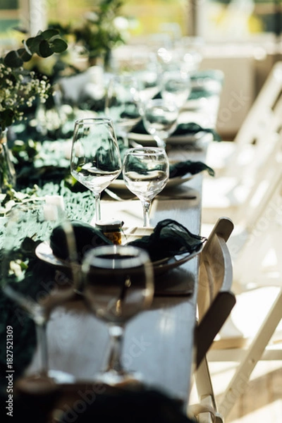 Fototapeta Elegant festive table setting with green decor and glassware