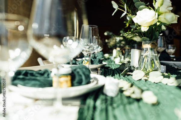 Fototapeta Elegant festive table setting with green decor and glassware