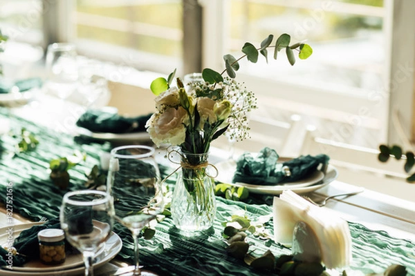 Fototapeta Elegant festive table setting with green decor and glassware