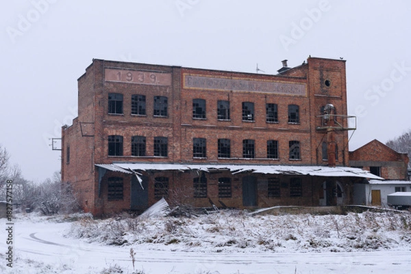 Obraz Old derelict brick building stands in winter scenery with signs of long-term neglect. Concept of disappearing industry, architectural history, educational materials and urban studies.