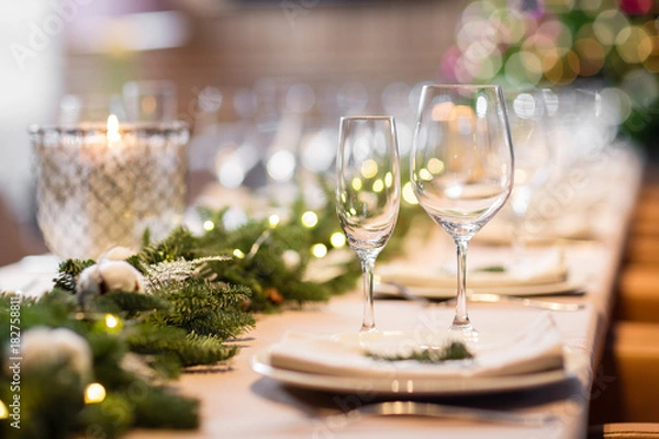 Fototapeta Christmas dinner feast. A decorated dining table with champagne glasses and christmas tree in background