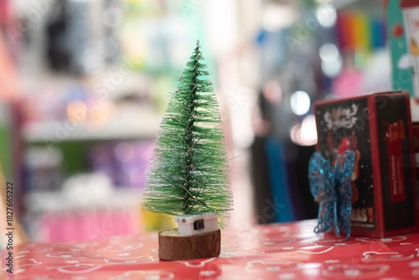 Obraz Miniature Christmas Tree on Red Table with Bokeh Background