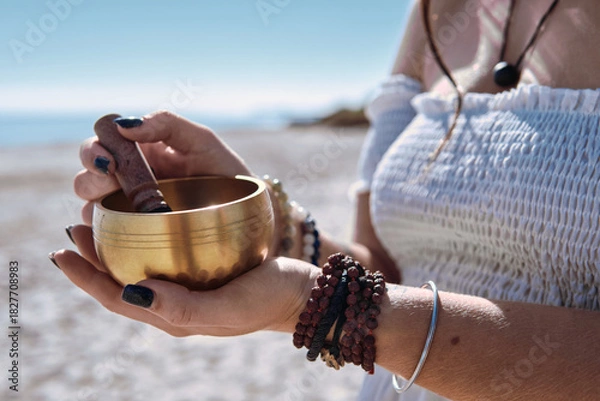 Fototapeta Close up woman begins to play Tibetan bowl with wooden mallet, representing sound healing and meditative focus. Concept of energy of mindfulness and the soothing vibration of inner calm