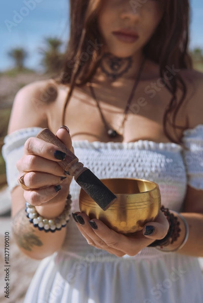 Fototapeta Close up woman begins to play Tibetan bowl with wooden mallet, representing sound healing and meditative focus. Concept of energy of mindfulness and the soothing vibration of inner calm