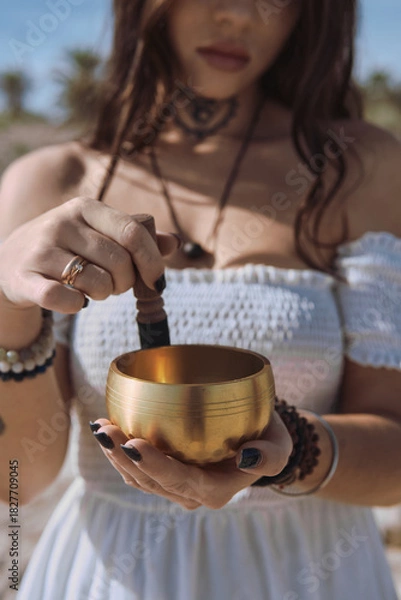 Fototapeta Close up woman begins to play Tibetan bowl with wooden mallet, representing sound healing and meditative focus. Concept of energy of mindfulness and the soothing vibration of inner calm