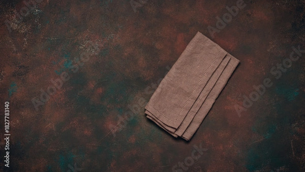 Fototapeta Brown linen napkin on dark rusty grunge background, top view, flat lay, copy space, culinary backdrop