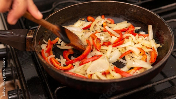 Fototapeta sauteing onion and bell peppers in a frying pan