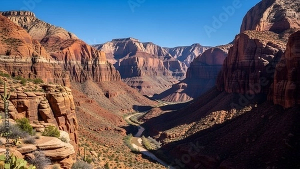 Fototapeta Panoramic view of a deep canyon with layers of red rock formations under a clear blue sky