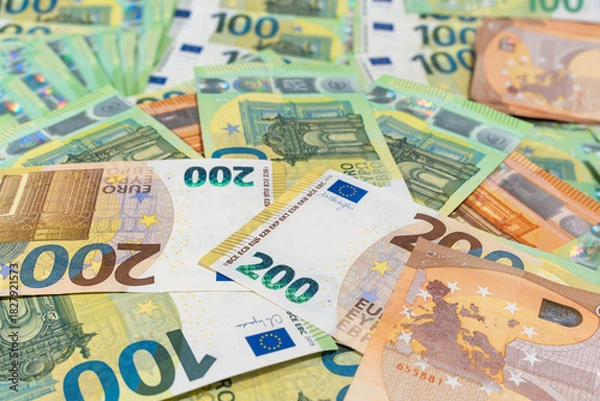 Fototapeta Scattered euro banknotes fill the frame in a bright flat lay. Background image for cash payments, currency, inflation, and European finance.