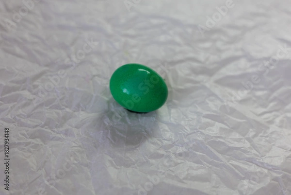 Fototapeta Brightly colored Easter eggs – various colors - green, yellow, red, blue – arranged on crumpled white paper. The eggs are smooth and shiny, ready for decoration or display at Easter