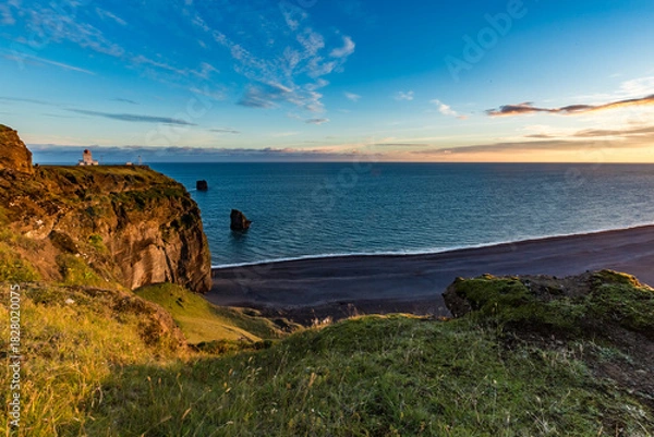 Fototapeta Stunningly beautiful sunset over the ocean as seen from the cape cliffs near the lighthouse of Vik, small city in Southern Iceland, travel tourist destination and sightseeing