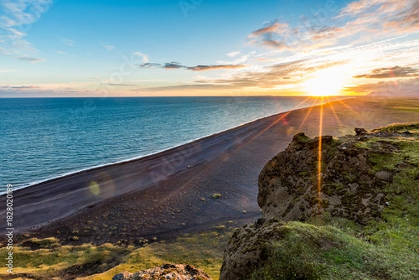 Fototapeta Stunningly beautiful sunset over the ocean as seen from the cape cliffs near the lighthouse of Vik, small city in Southern Iceland, travel tourist destination and sightseeing