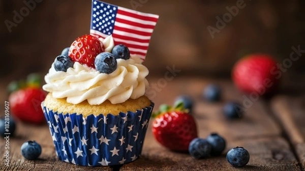 Obraz A patriotic cupcake adorned with fresh blueberries, a strawberry, and a miniature american flag, sitting on a rustic wooden surface