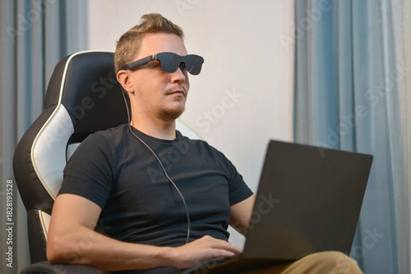 Obraz Man Using Wearable AR XR Smart Glasses While Using Laptop