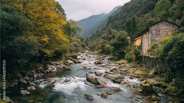 Fototapeta A scenic mountain river flows through a valley with colorful autumn trees and a rustic stone building on a rocky embankment