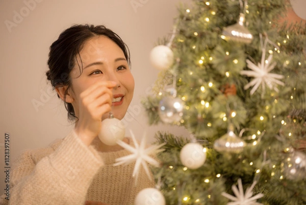 Obraz 夜の白熱灯など部屋でクリスマスの飾りつけをするかわいい女性クローズアップ