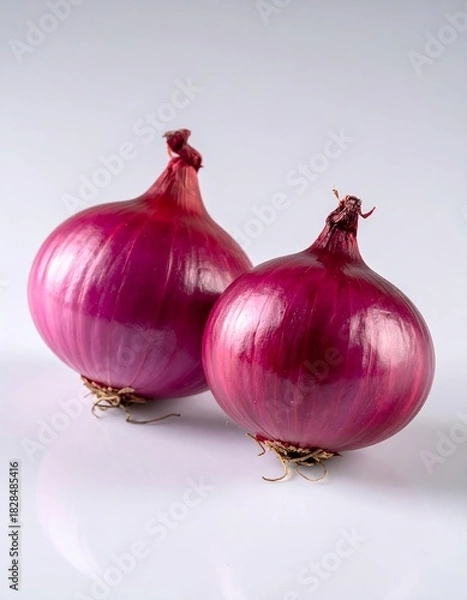 Obraz Two vibrant red onions on a reflective white surface, studio shot