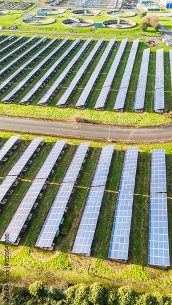 Fototapeta Side drone view of a solar farm in portrait orientation, clean renewable energy powered by sunlight