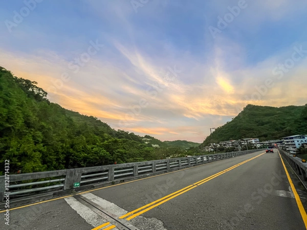 Fototapeta Stunning dawn sky in Wulai, New Taipei City, Taiwan. Dramatic golden and orange clouds illuminate the morning sky above silhouetted mountain ranges and forest.