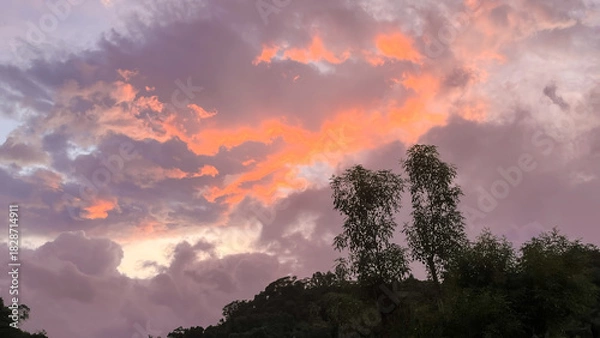 Fototapeta Dramatic dawn sky over Wulai, New Taipei City, Taiwan, featuring vibrant pink, orange, and purple altocumulus clouds above the dark silhouette of the hills and trees.