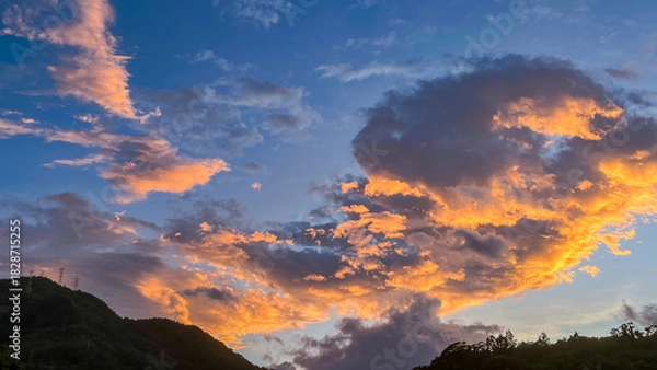Fototapeta Intense orange and golden sunrise clouds glowing dramatically above the dark mountain ridges of Wulai in New Taipei City Taiwan at early dawn.