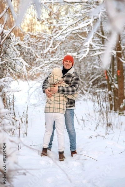Fototapeta Father and daughter playing and enjoying the snow in a winter forest. Concept of family joy, warm emotions, childlike happiness, and fun winter activities outdoors.