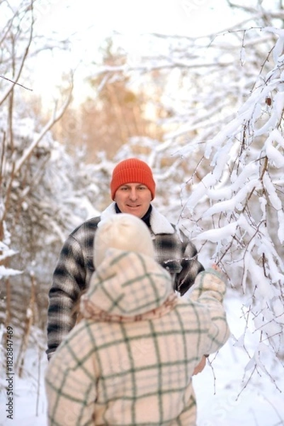 Fototapeta Father and daughter playing and enjoying the snow in a winter forest. Concept of family joy, warm emotions, childlike happiness, and fun winter activities outdoors.