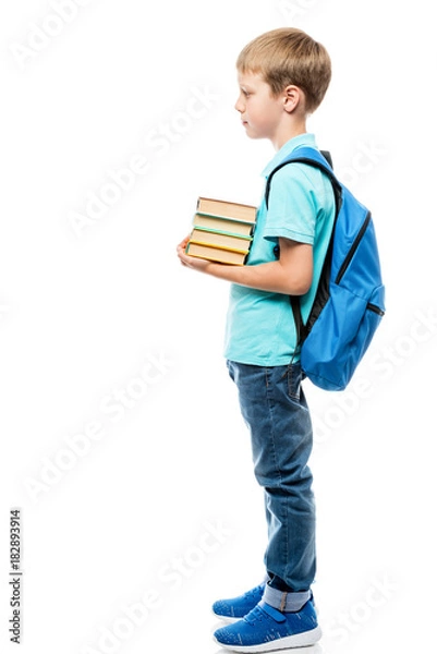 Fototapeta schoolboy with a bunch of books and a backpack on a white background in full length side view