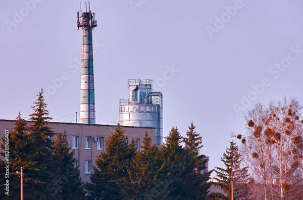 Obraz Factory with smokestack and industrial structure against a clear sky in an urban area