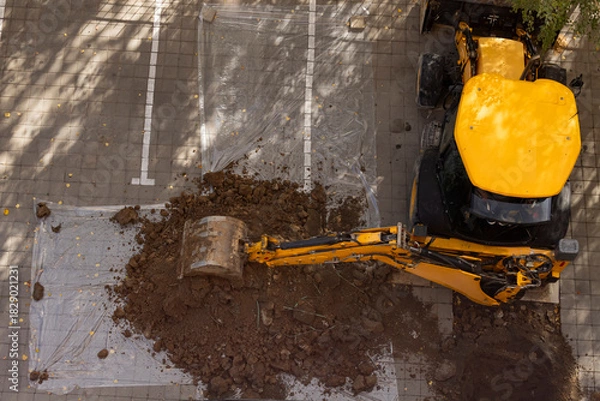 Fototapeta Excavator digging on paved ground top view