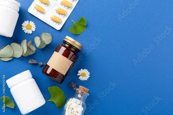 Fototapeta Herbs and flowers with medicines on color background, top view