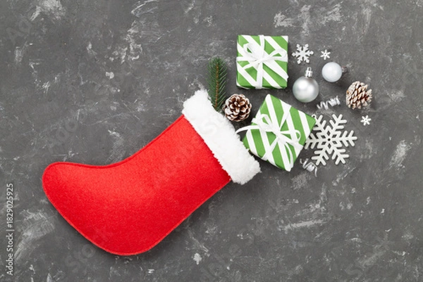 Fototapeta Christmas sock with gifts and decoration on concrete background, top view