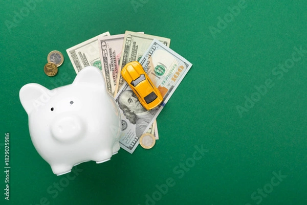 Fototapeta Piggy bank with money and model of car on color background, top view