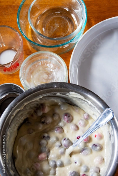 Fototapeta Thick cranberry cake batter, showing moist texture and suspended fruit, being stirred in a bowl. A key step in homemade holiday baking.