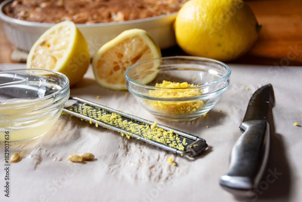 Fototapeta Preparing fresh lemon glaze: zest, juice, lemon rinds, and microplane near the baked cranberry cake. Natural, homemade food preparation.
