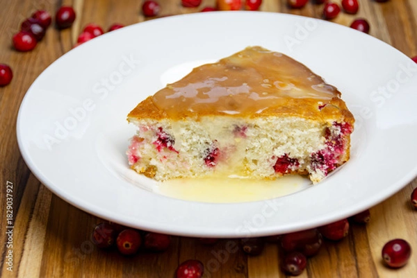 Fototapeta Final served slice of homemade cranberry cake with lemon glaze, showcasing the moist crumb and glistening drizzle on a clean white plate. Delicious dessert.