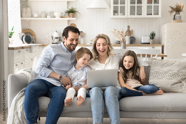Obraz Joyful laughing couple with small children watching videos on notebook